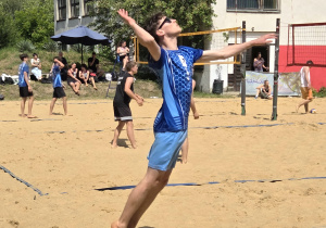 Uczeń podczas serwu w meczu siatkówki plażowej